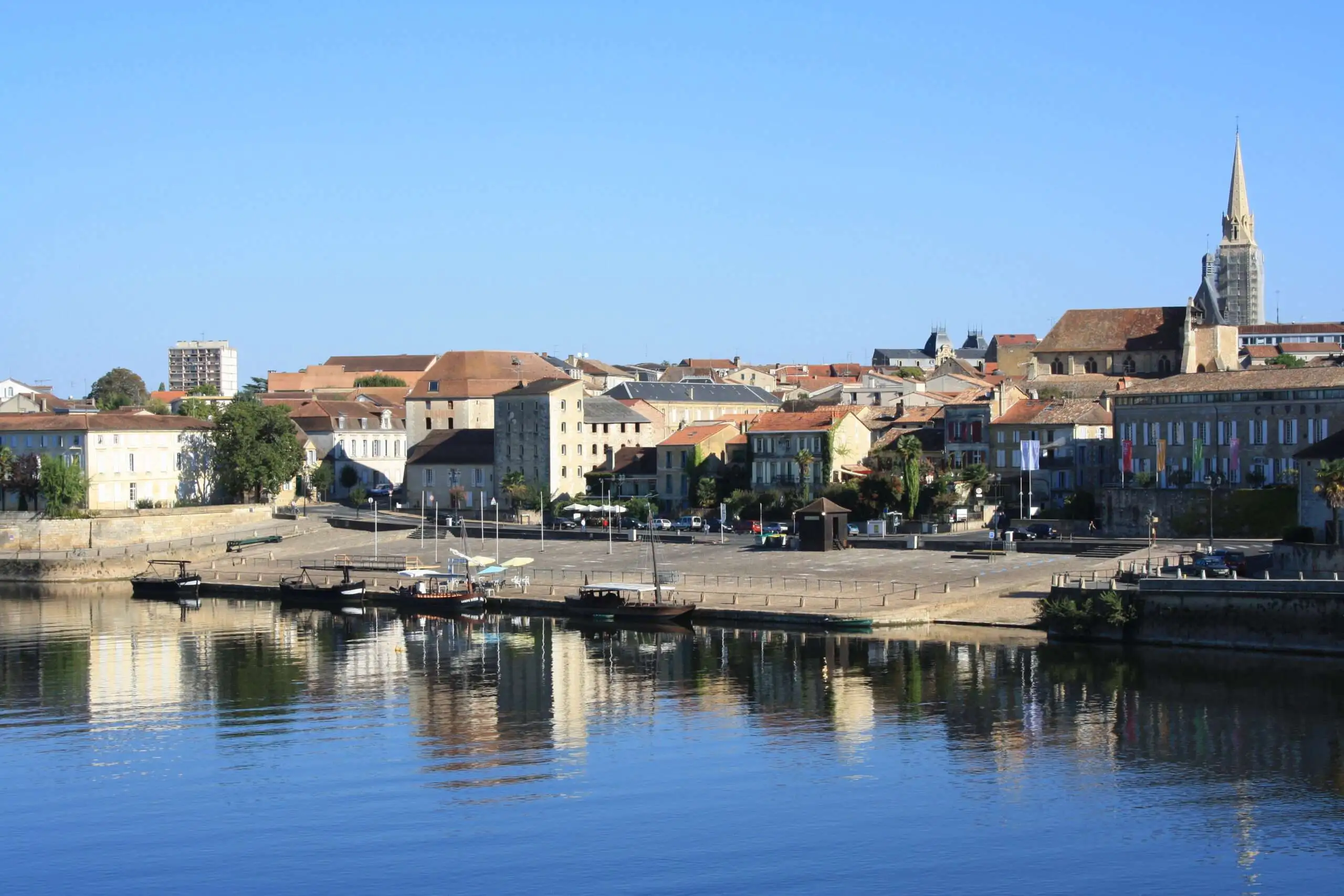 Vue sur le port de bergerac, au premier plan, la Dordogne avec des gabarres.