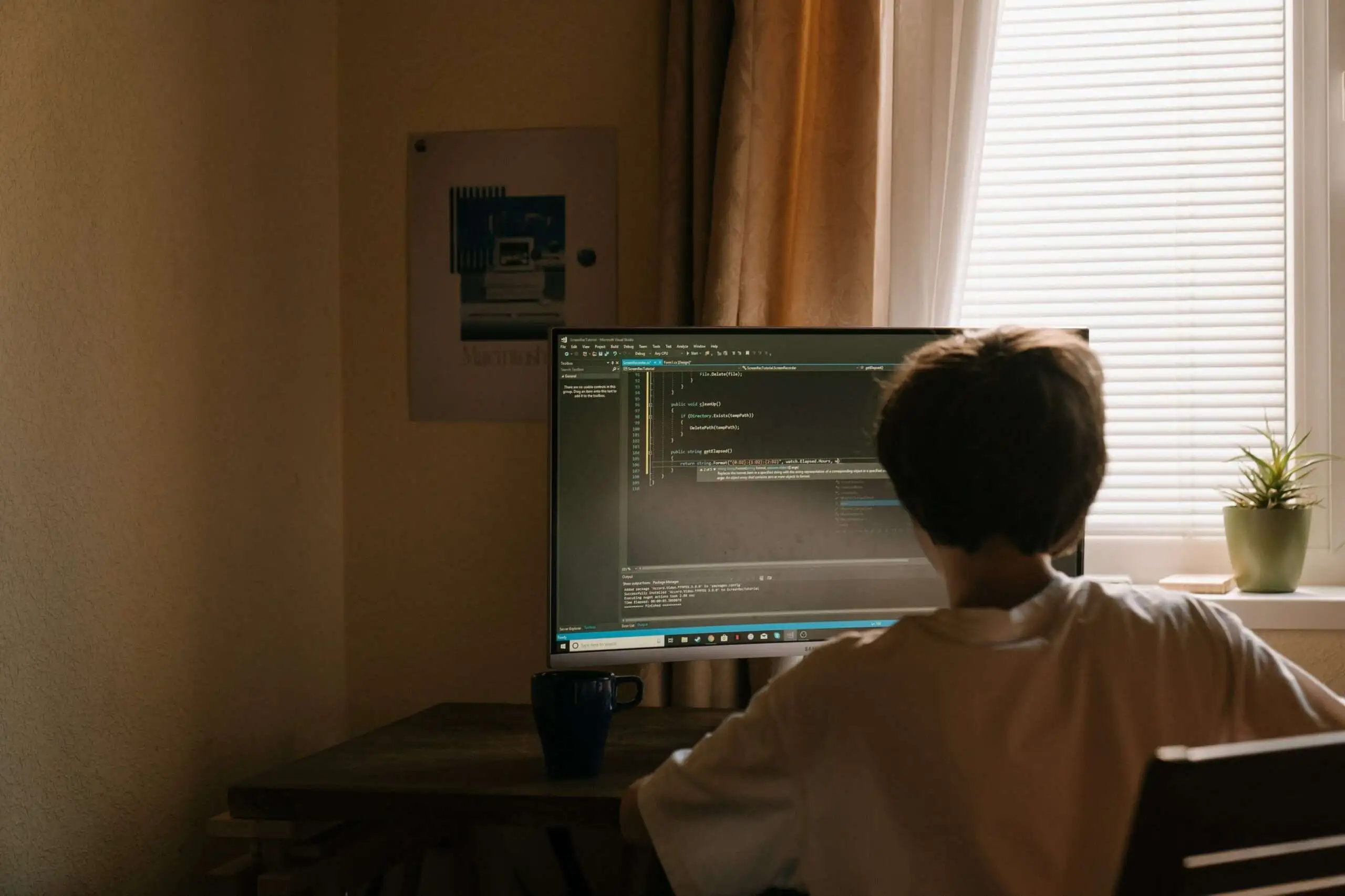 un-jeune-homme-sur-son-ordinateur. Un jeune homme sur son ordinateur en train de créer son site web en codant.