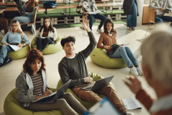 Formateur interrogeant ses élèves assis sur des poufs dans une salle de classe.