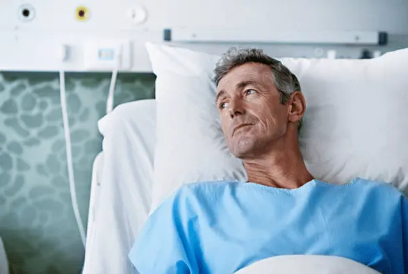 Un homme malade dans sont lit d'hôpital.