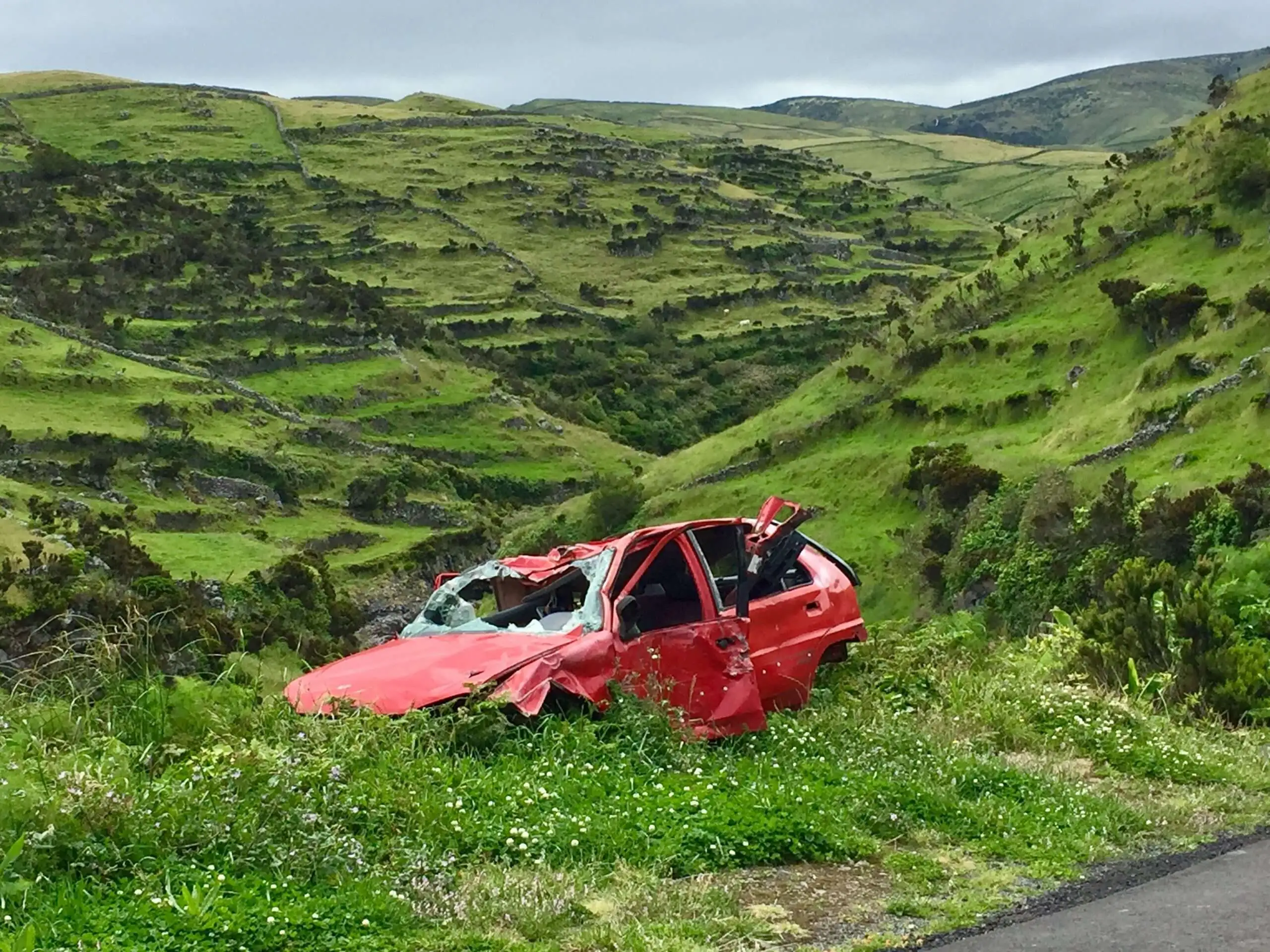 Une voiture accidentée à flanc de colline.
