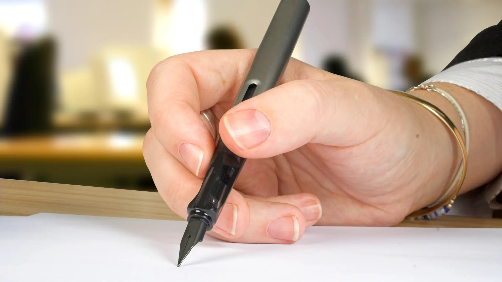 Zoom sur la main d'une personne écrivant une lettre de motivation au stylo.